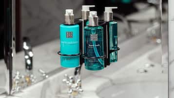 A bathroom with a mirror reflecting three bottles of hand and body lotion.
