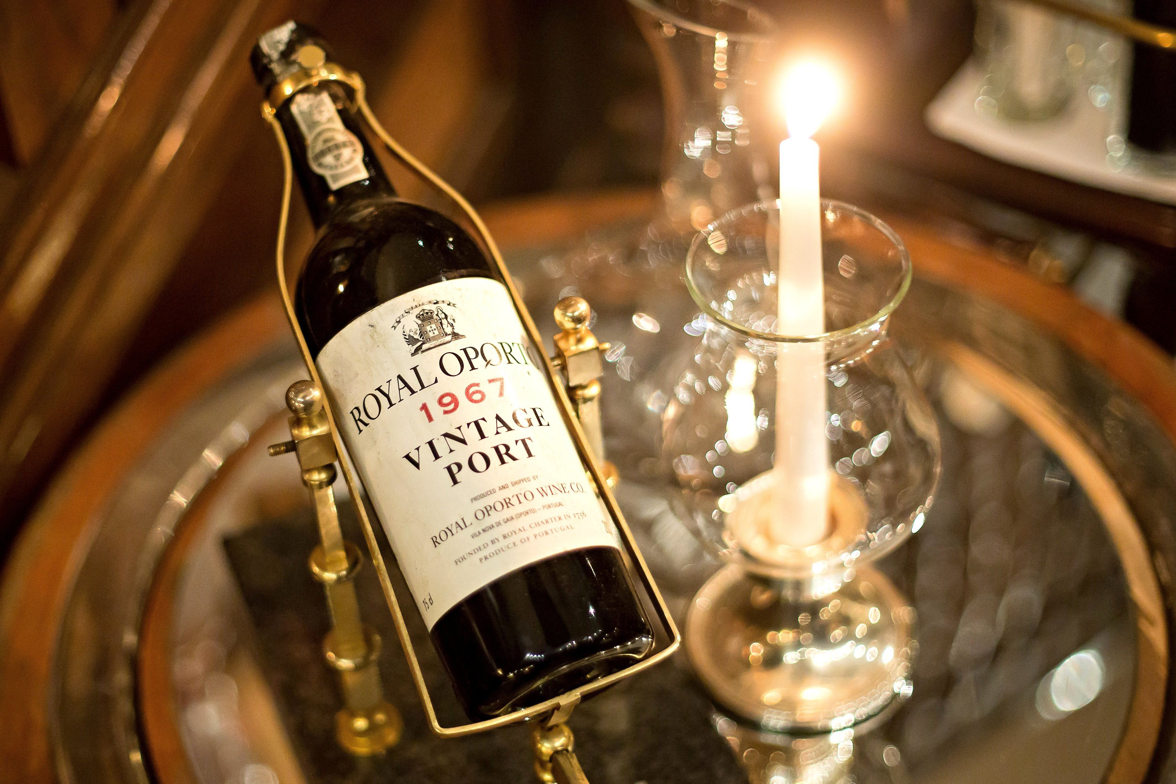 En flaske Royal Porto Vintage Port vin på et fad med et lys.