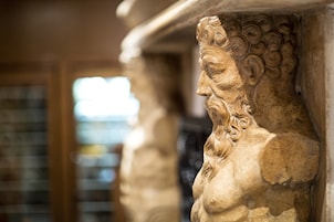Un primo piano di una colonna in pietra con elaborate decorazioni, probabilmente parte dell'architettura di un edificio storico.