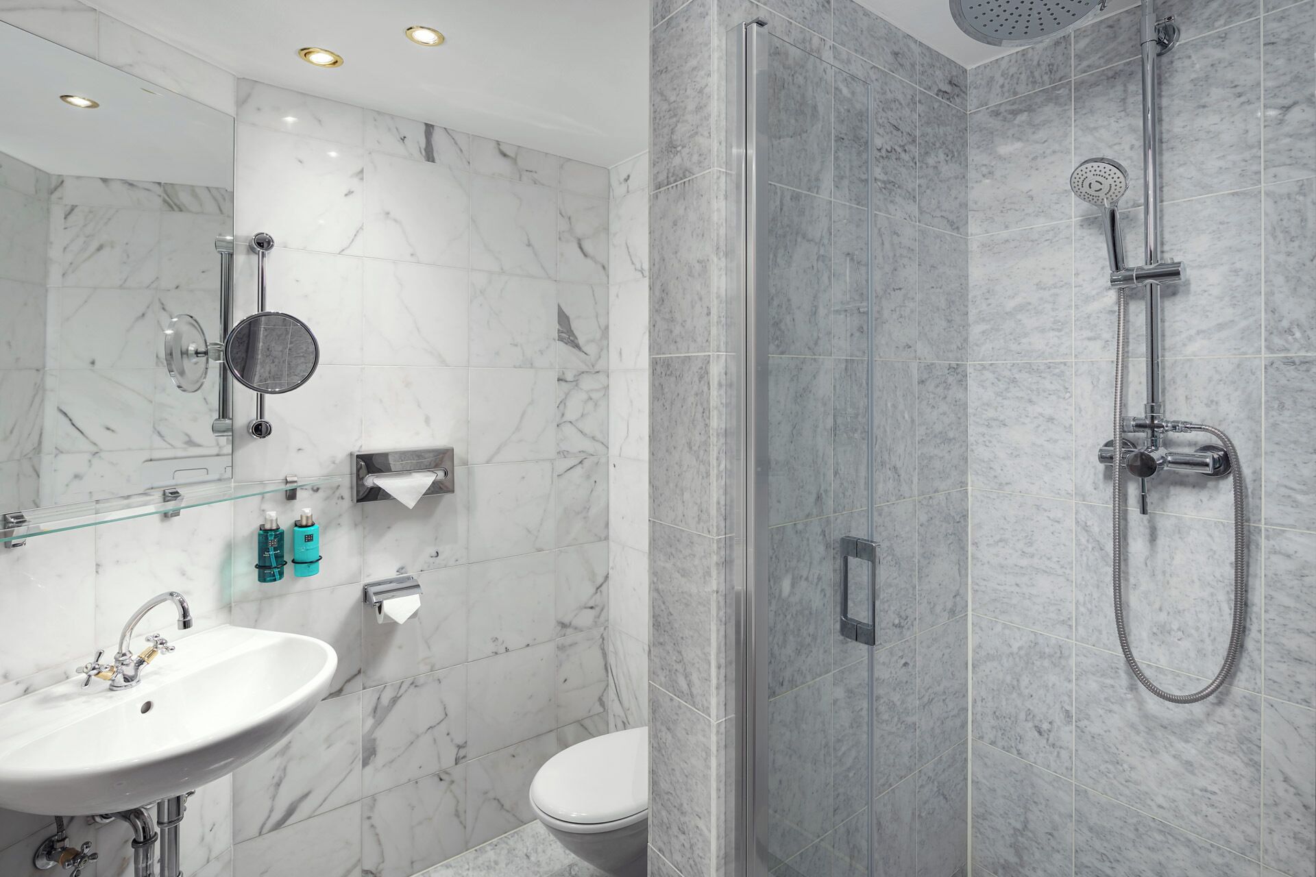 A modern bathroom with a glass shower enclosure, a sink, and a toilet.