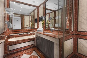 Un bagno di lusso con piani in marmo, uno specchio grande, una vasca e una doccia.
