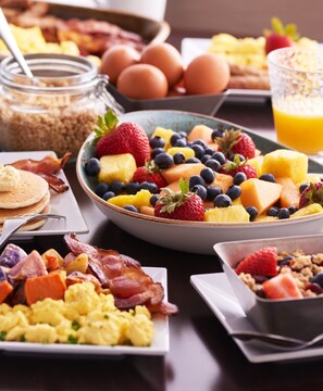 A breakfast spread with various dishes including scrambled eggs, bacon, pancakes, and a fruit bowl with strawberries, blueberries, and pineapple. - Hyatt Place Dallas/Grapevine (Grapevine)