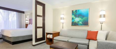 Une chambre d’hôtel avec un lit, un canapé, une table basse et un tableau au mur.