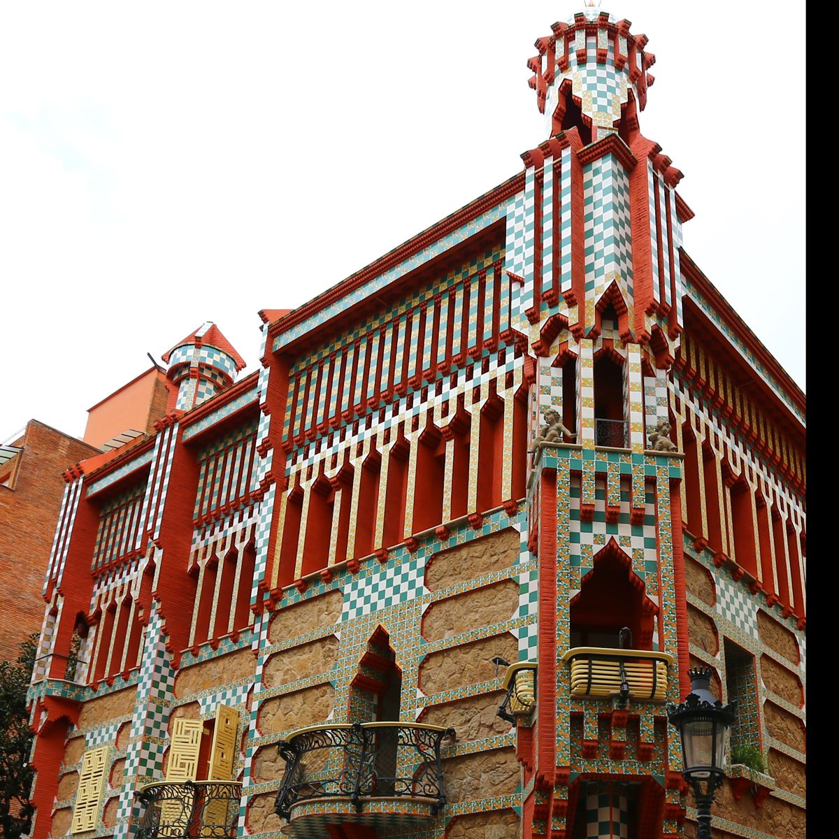A building with a checkered facade, red and white accents, and a tower with a spire.