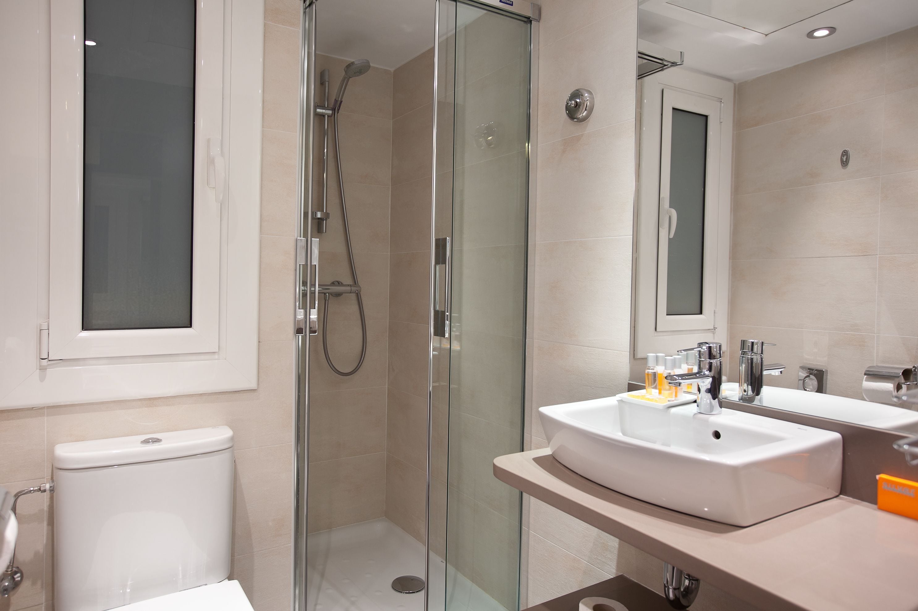 A modern bathroom with a glass-enclosed shower, a white sink, and a large mirror.