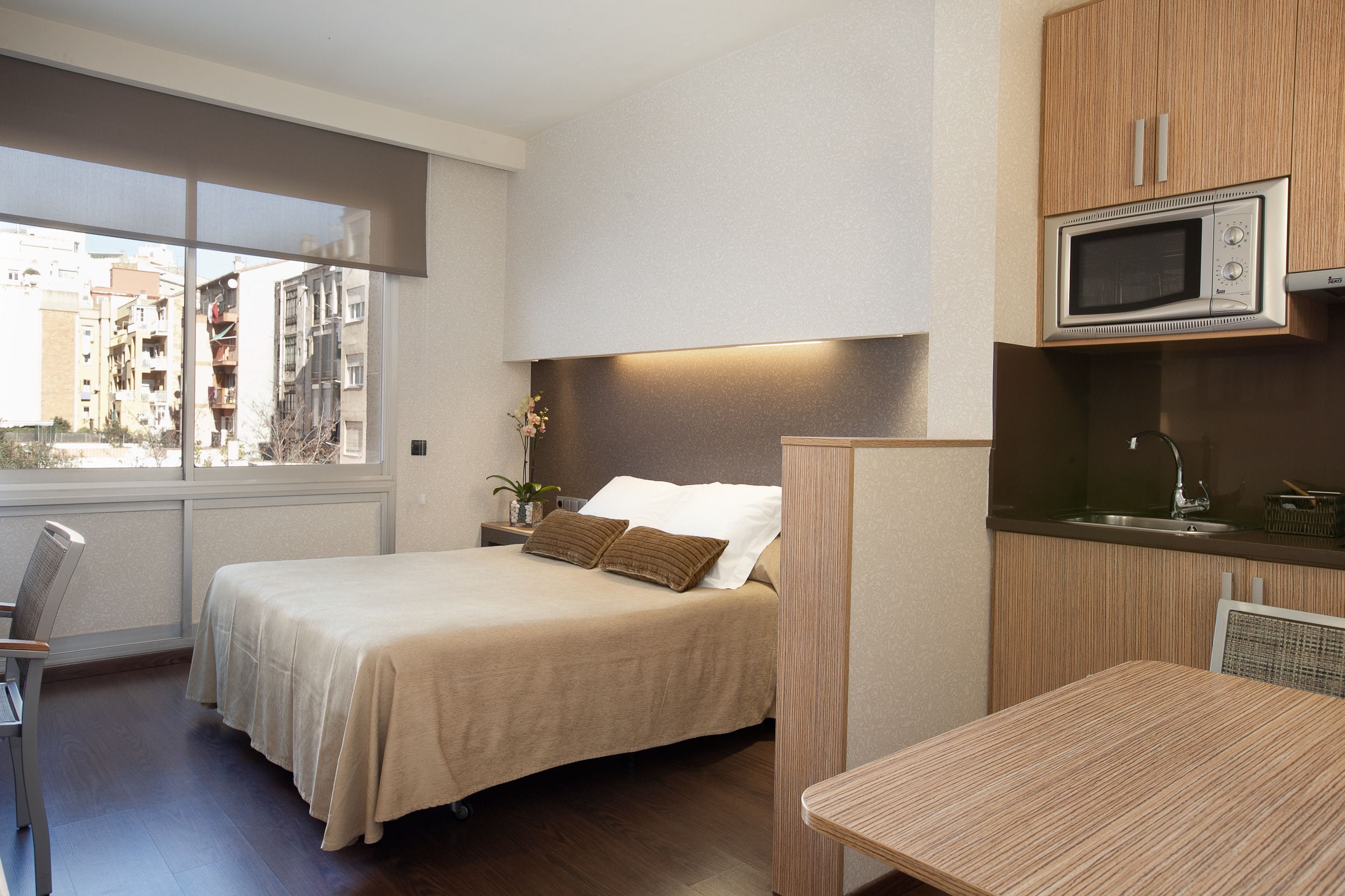 Une chambre d’hôtel équipée d’un lit, d’un bureau, d’un four à micro-ondes et d’une fenêtre donnant sur des immeubles.
