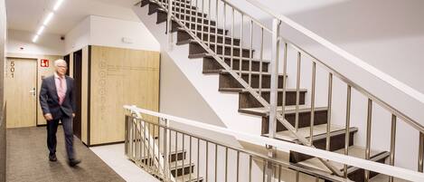 A modern interior with a staircase, a wooden door labeled "501", and a person walking.