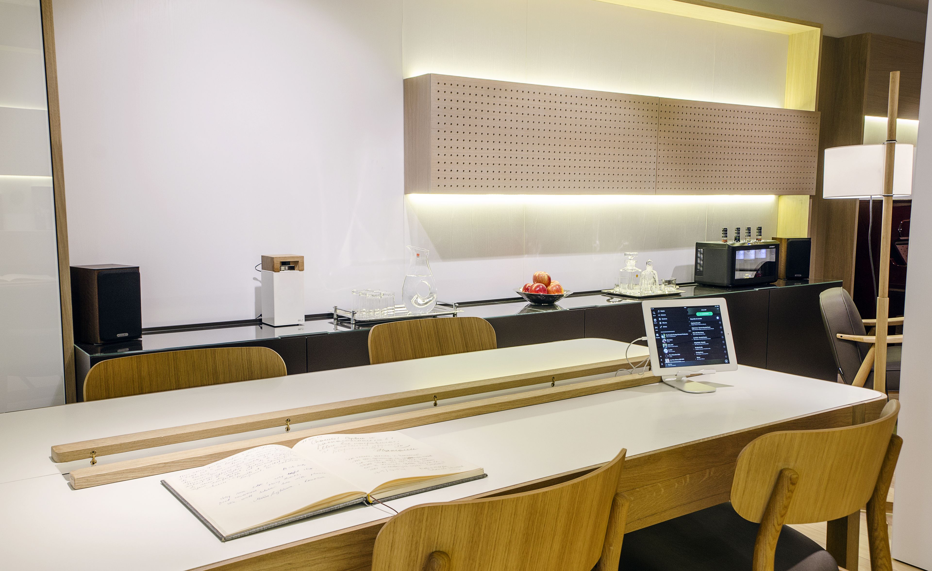 A modern conference room with a long table, chairs, a laptop, and a whiteboard.