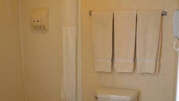A bathroom with a bathtub, toilet, and two towels hanging on the wall.