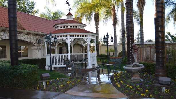 A gazebo with a red roof, surrounded by palm trees and a fountain. - Dynasty Suites Redlands (Redlands)