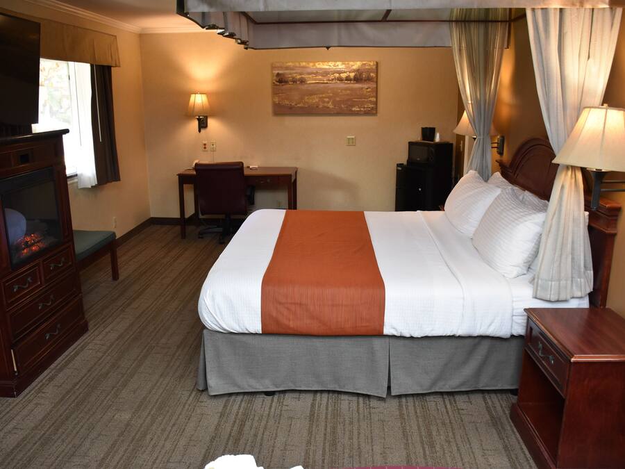 Une chambre d’hôtel avec un grand lit, un bureau, une télévision et une cheminée.