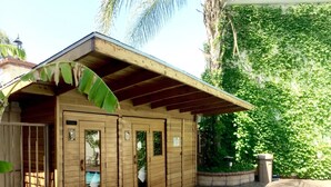 A wooden building with multiple rooms, a covered patio, and a pool area. - Dynasty Suites Redlands (Redlands)