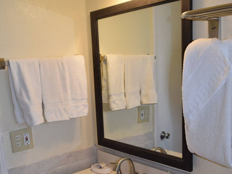 A bathroom with a white sink, two faucets, a mirror, and two wall-mounted lights.