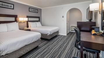 Quarto de hotel com duas camas, uma mesa, uma cadeira e um abajur.