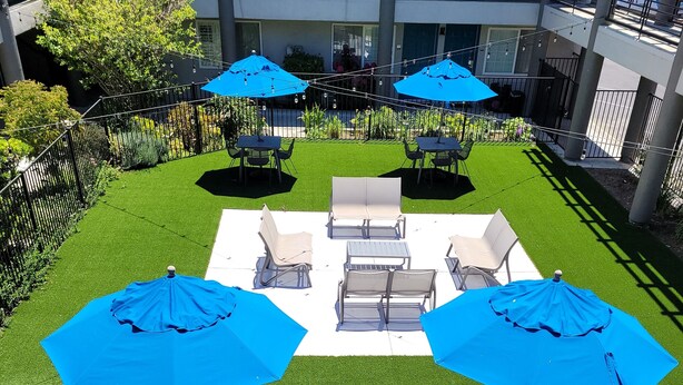 A patio area with outdoor seating and blue umbrellas. - Redwood Creek Inn (Redwood City)