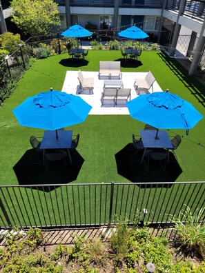 A patio area with outdoor seating and blue umbrellas. - Redwood Creek Inn (Redwood City)