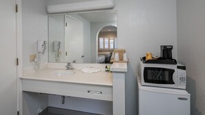 A bathroom with a sink, mirror, hair dryer, and a microwave on a small cabinet. - Redwood Creek Inn (Redwood City)