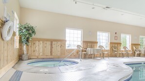 A pool area with a hot tub, wooden walls, and several chairs.