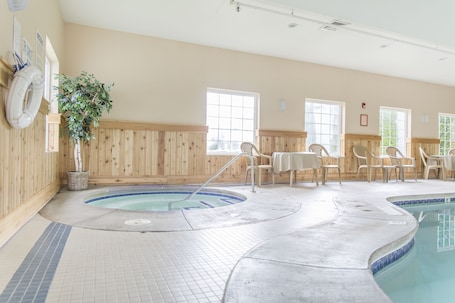 A pool area with a hot tub, wooden walls, and several chairs.