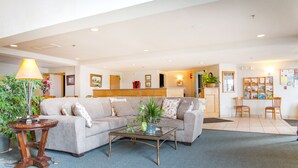 A spacious living area with a sofa, coffee table, and a lamp. There is a reception desk and a small dining area with chairs.