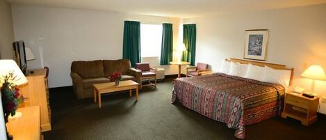 A hotel room with a bed, a sofa, a desk, a chair, and a lamp.