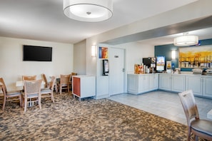 Een hotelkamer met een eethoek, een kitchenette en een groot raam.