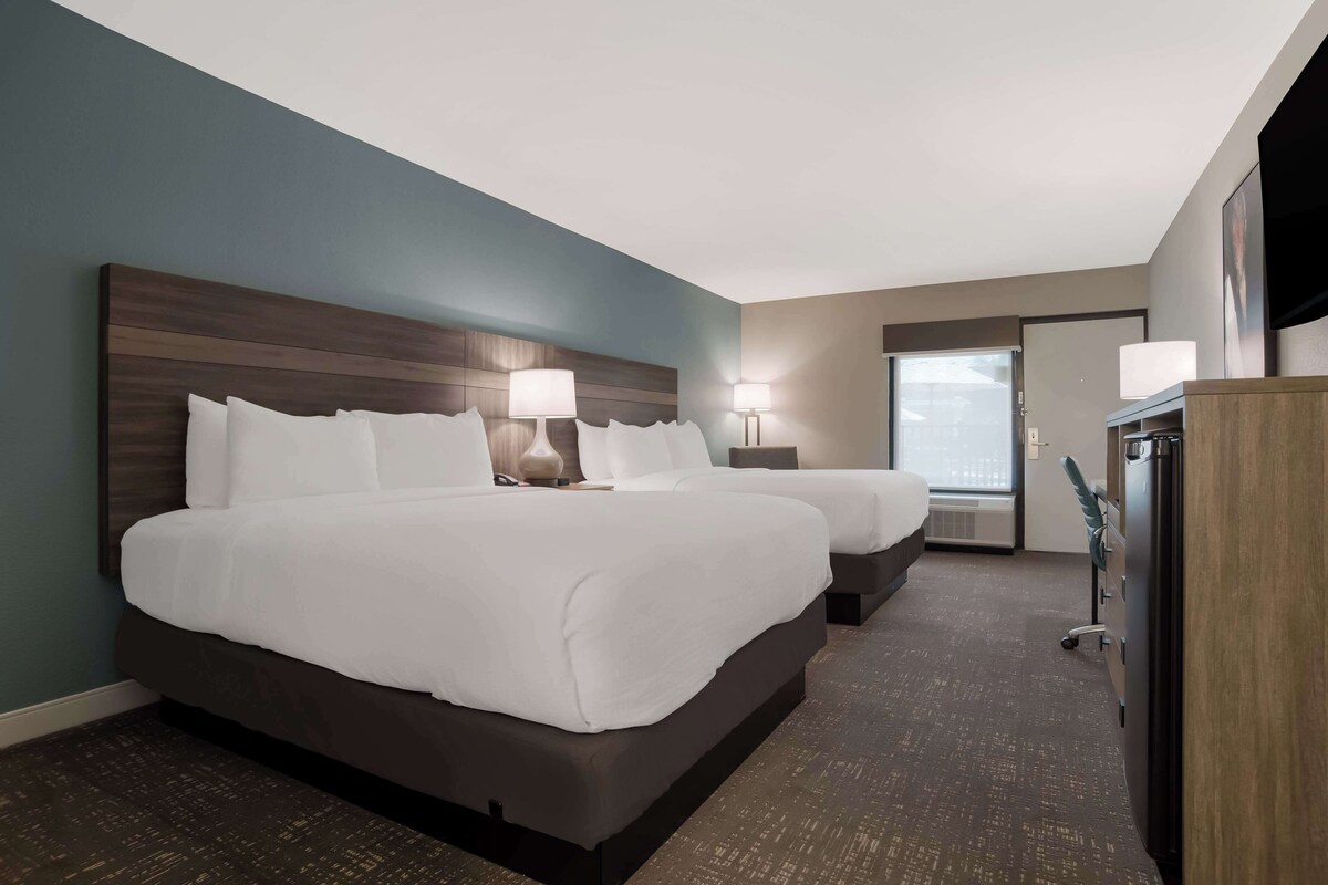 A hotel room with two beds, a desk, and a wardrobe.
