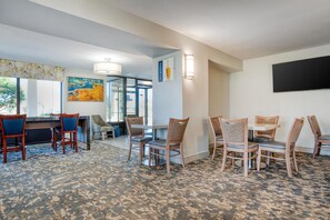 Habitación de hotel con zona de comedor, un cuadro en la pared y vistas al exterior.