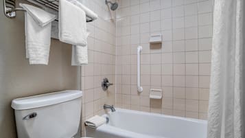 Un baño con inodoro, bañera y cabezal de ducha.