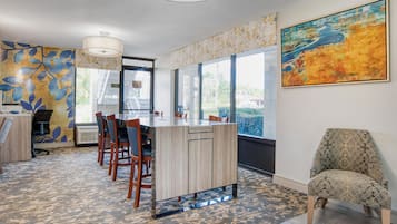 Un comedor moderno con una isla central, sillas y un gran ventanal que ofrece vistas.