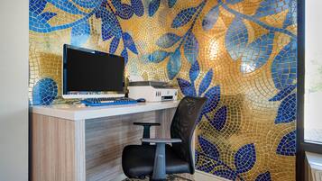 A workspace with a computer, printer, and office chair against a wall with a mosaic pattern.