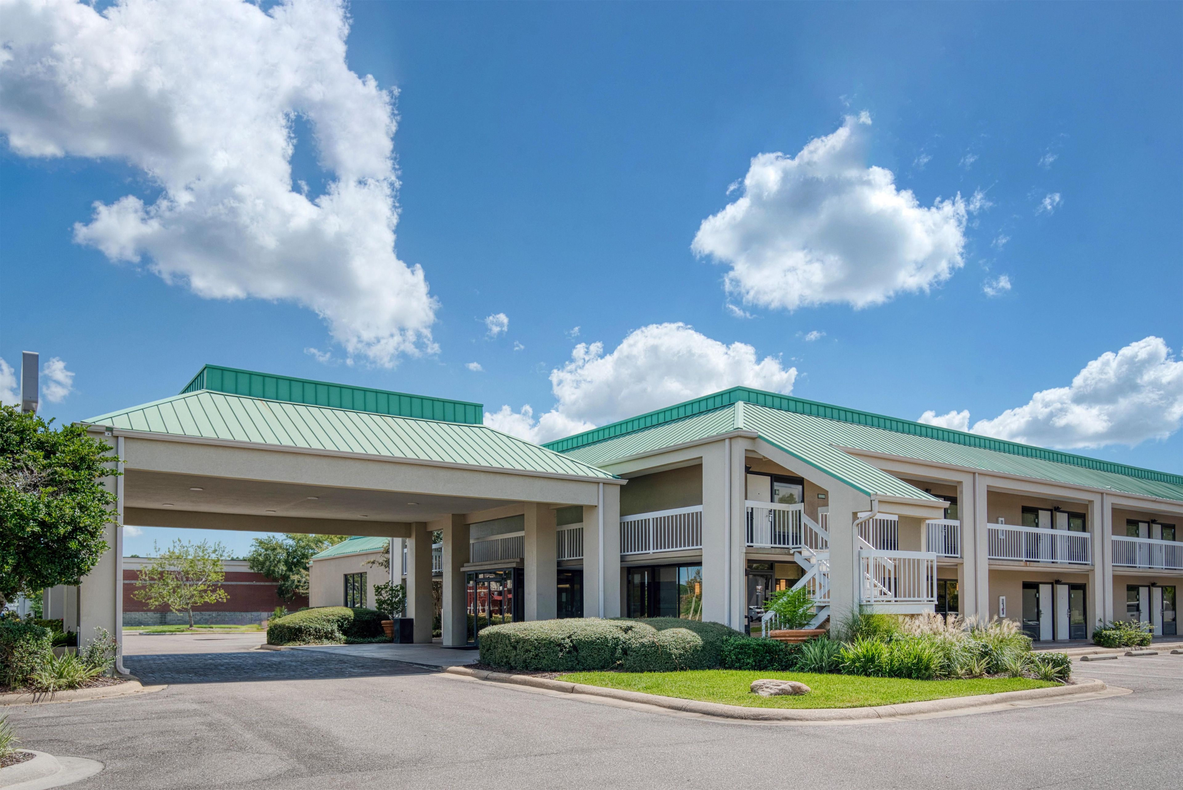 A hotel with a covered parking area, multiple floors, and a green roof.