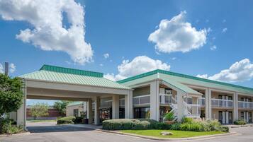 A hotel with a covered parking area, multiple floors, and a green roof.
