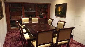 A conference room with a wooden table, six chairs, and a bookshelf filled with books.