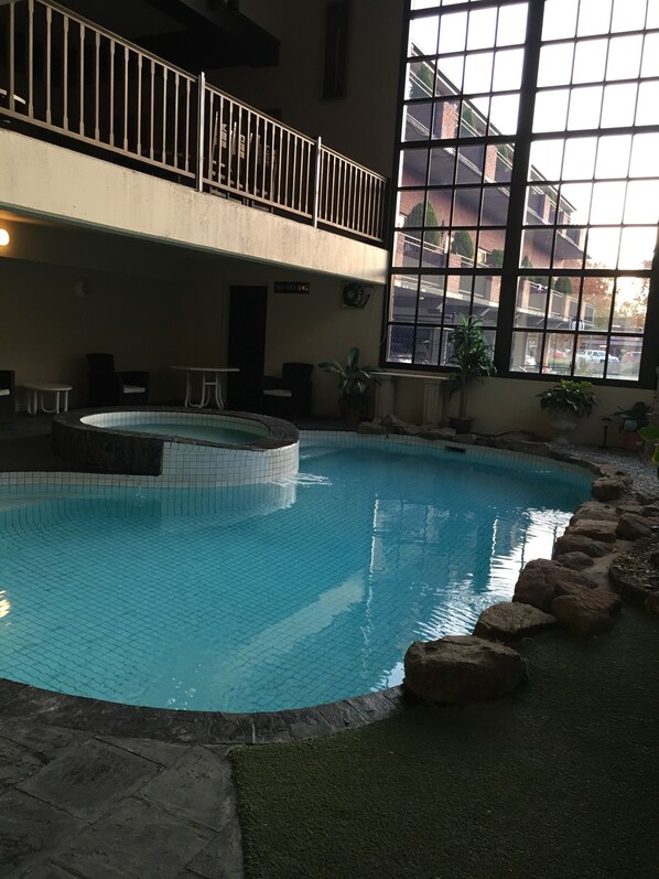 An indoor swimming pool with a tiled floor, surrounded by rocks and potted plants. - Albury Manor House (Albury)