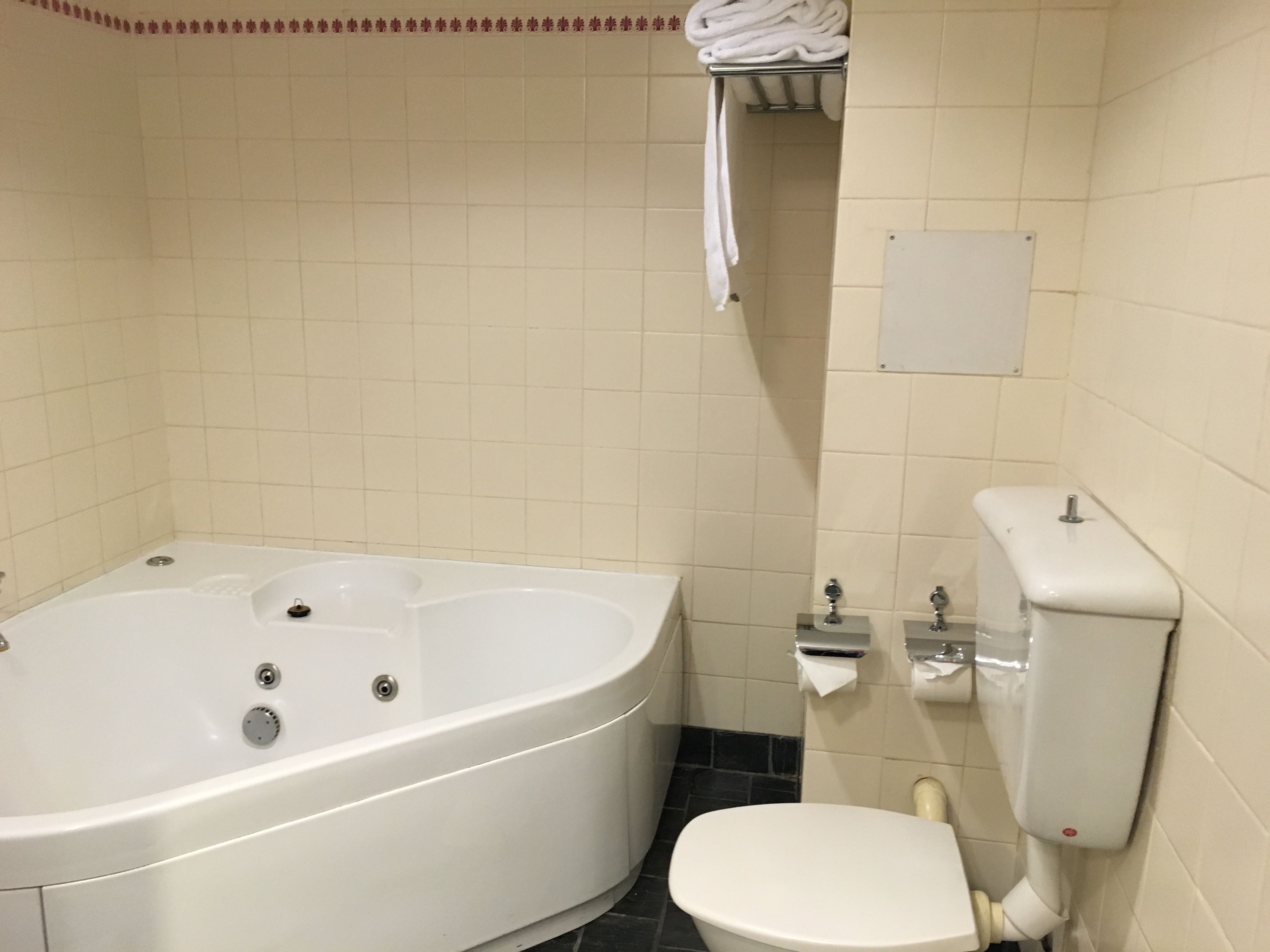 Un baño con bañera, inodoro y toallero.