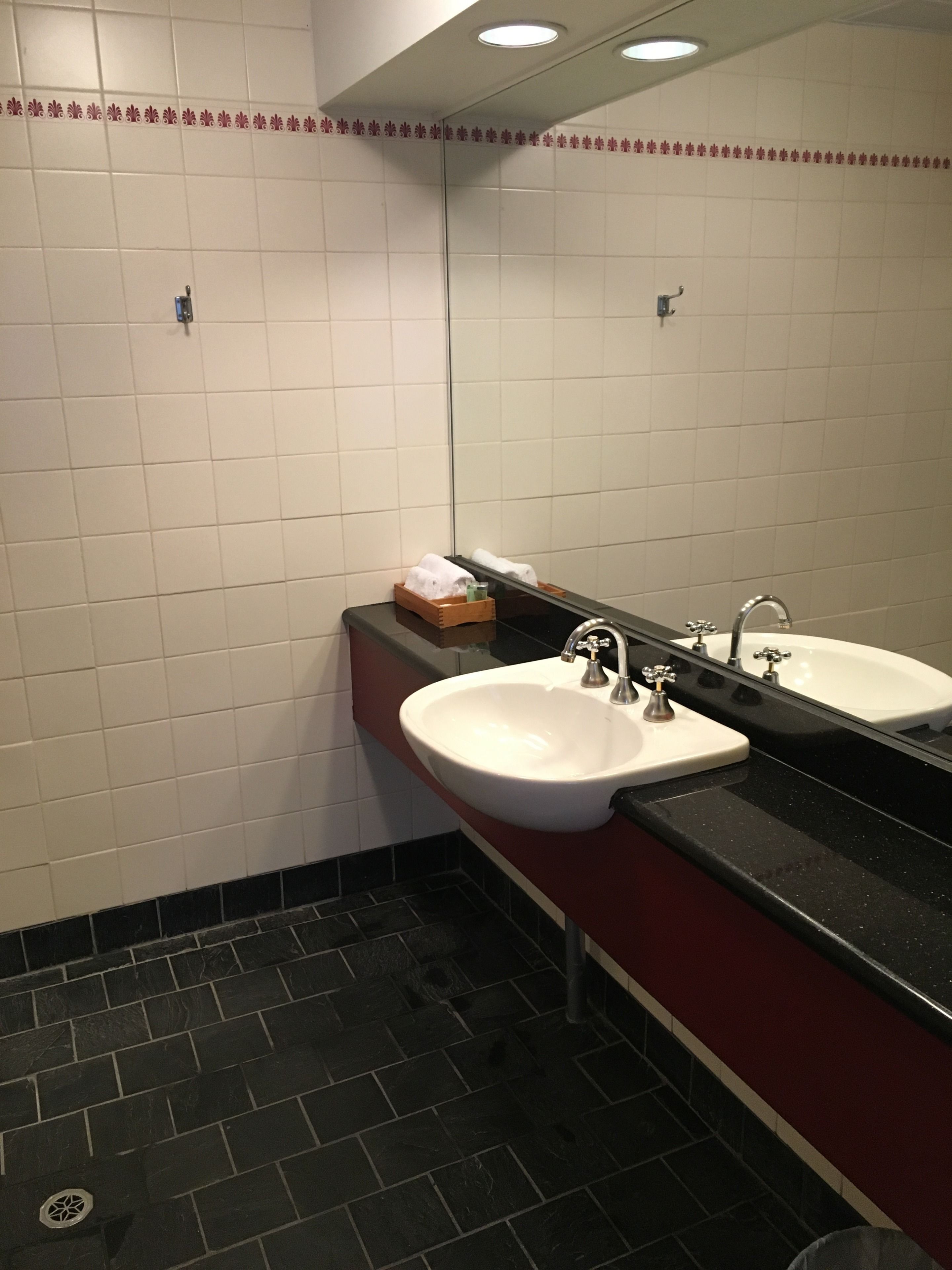 A bathroom with two sinks, a mirror, and a tiled floor.