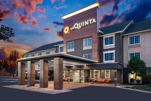 Ein La Quinta Hotel mit moderner Fassade, großzügigem Eingangsbereich und Außenbereich mit Sitzgelegenheiten.