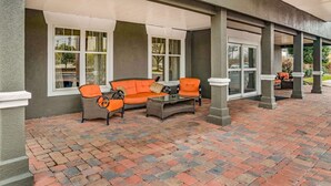 An outdoor patio area with a brick floor, two orange sofas, and a glass coffee table. - La Quinta Inn & Suites by Wyndham Cookeville (Cookeville)
