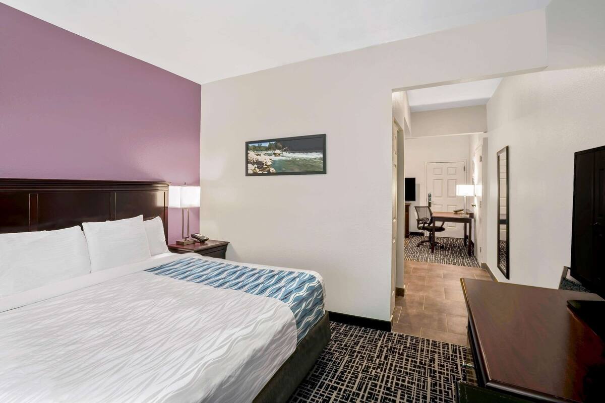A hotel room with a large bed, a desk, a chair, and a television.