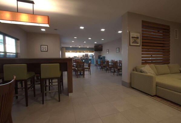 A spacious dining area with multiple tables and chairs, a bar area with stools, and a sofa.