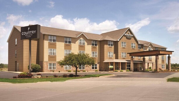 A Country Inn & Suites hotel with a covered entrance, multiple windows, and a landscaped front yard.