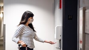 A person with a suitcase at the elevator door, indicating a hotel setting. - Country Inn & Suites by Radisson, Washington Dulles International Airport, VA (Sterling)