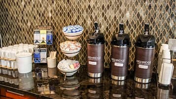 A buffet setup with various food items, condiments, and beverage dispensers.