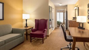 A hotel room with a sofa, a chair, a desk, and a lamp. - Country Inn & Suites by Radisson, Salina, KS (Salina)