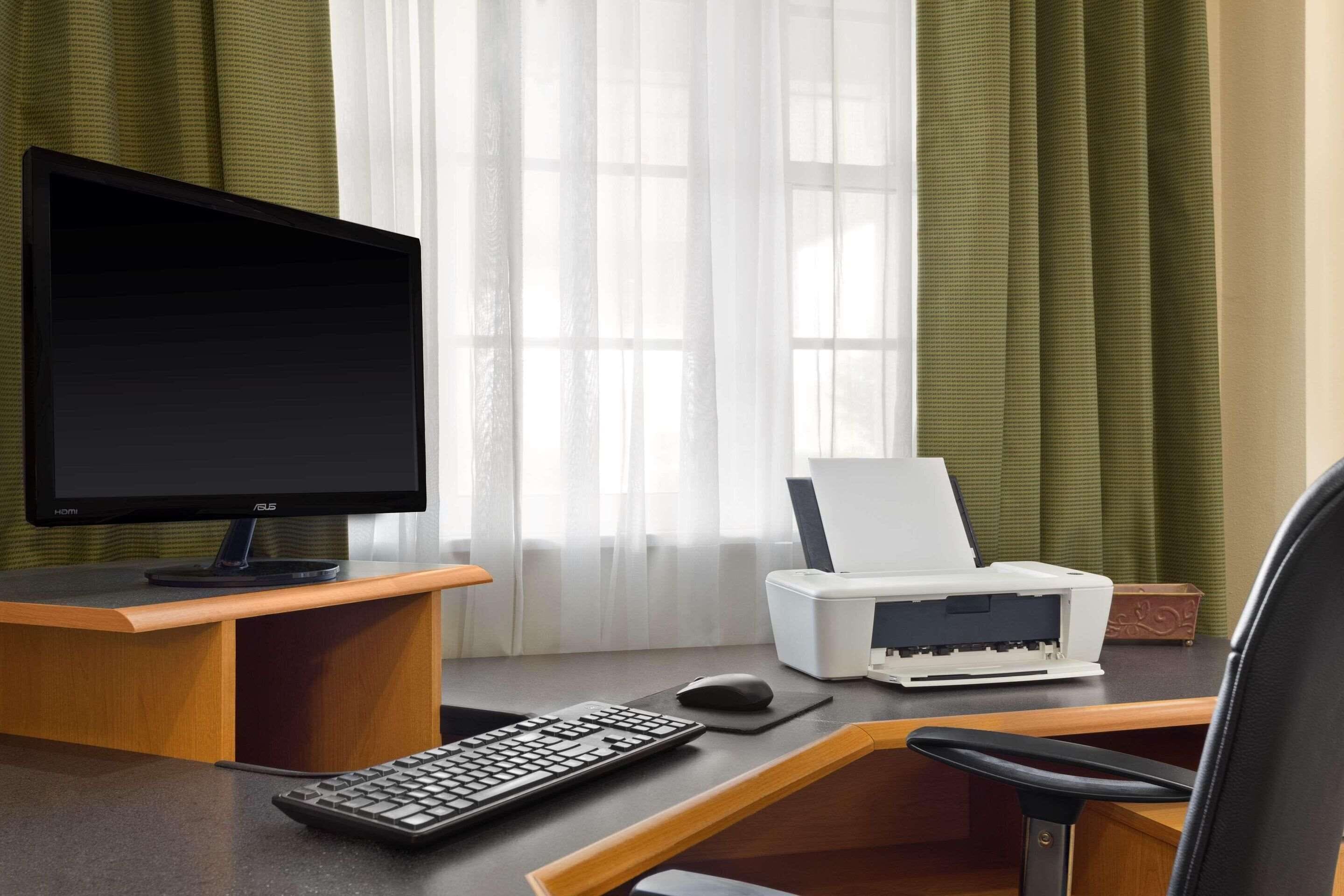 Un escritorio moderno de oficina con monitor de computadora, teclado, ratón e impresora.
