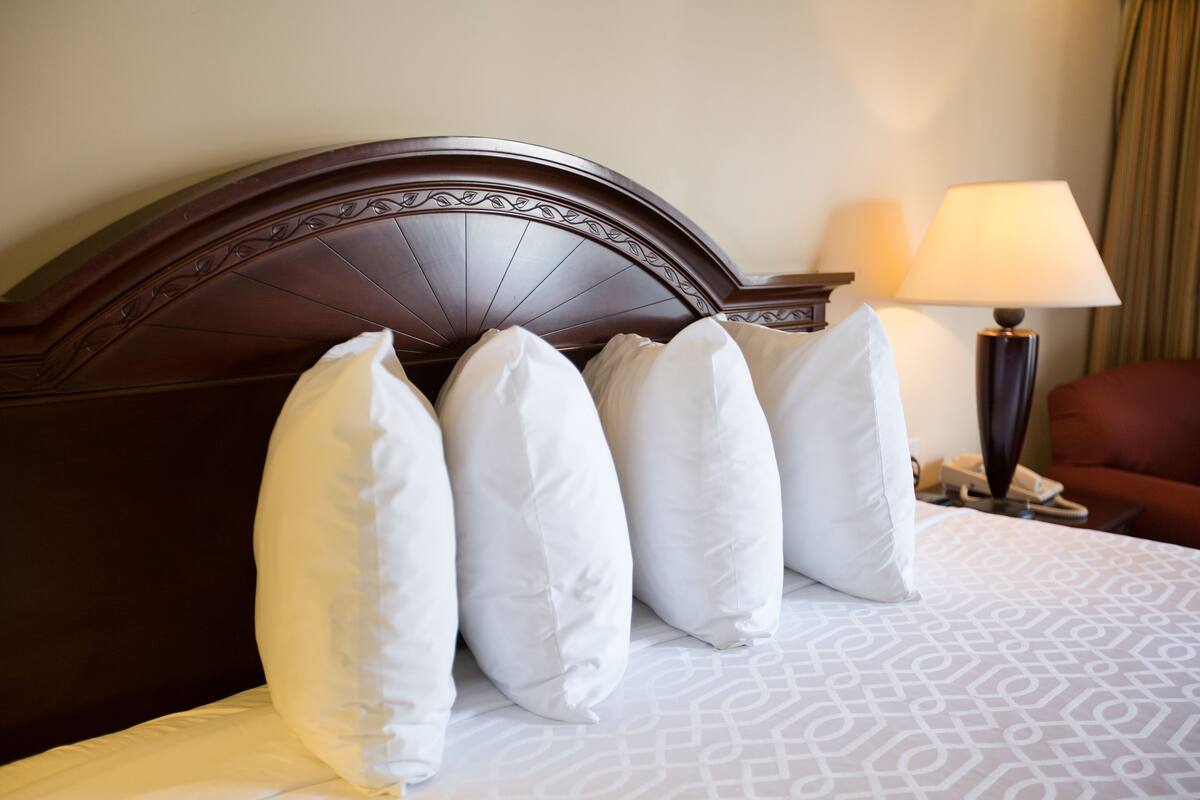 A neatly made bed with a patterned bedspread and a dark wooden headboard.