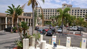 Ein Hotel mit Schwimmbad, Palmen und einem Parkplatz mit Autos.
