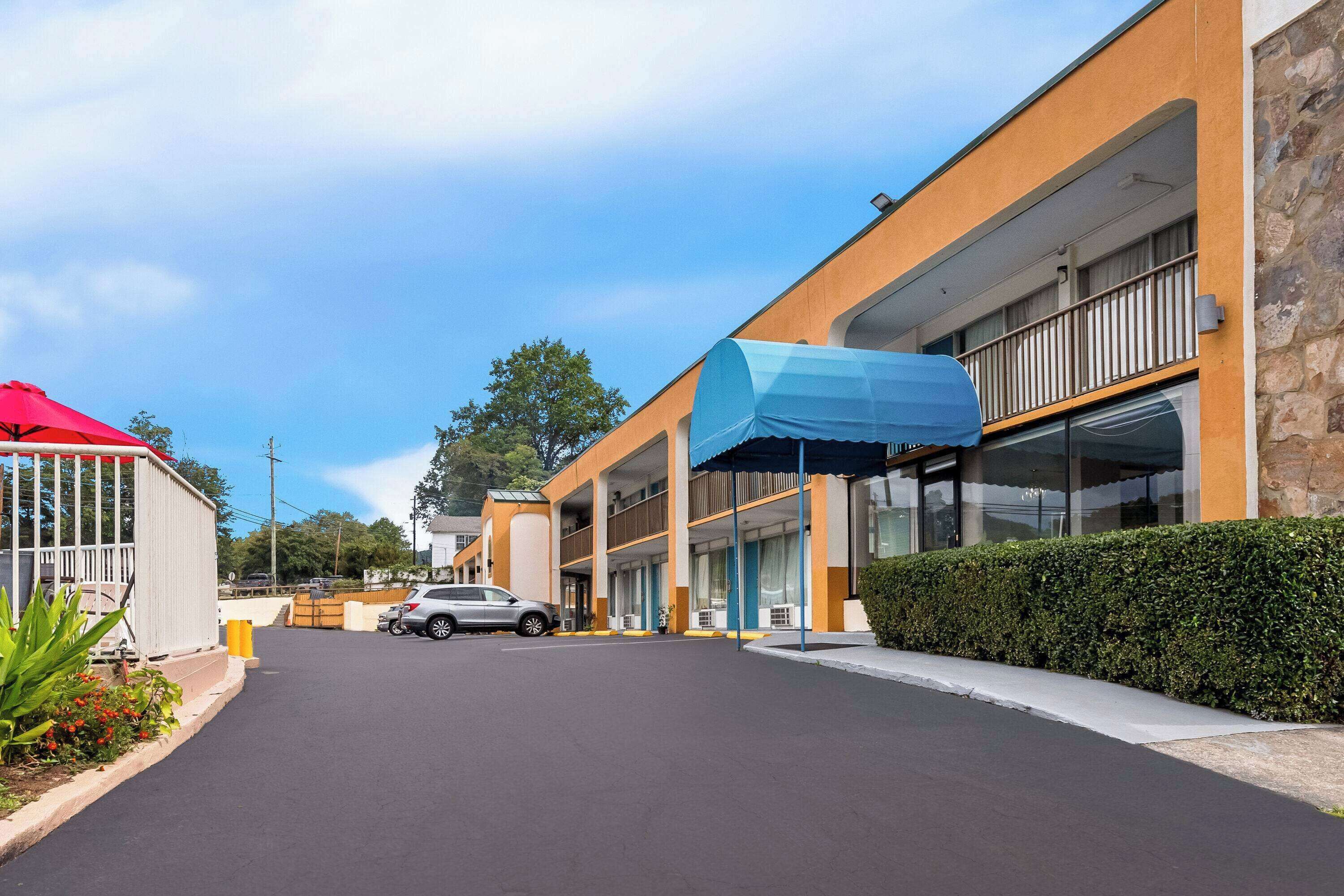 A hotel with a modern design, featuring a covered parking area and a building with multiple balconies.