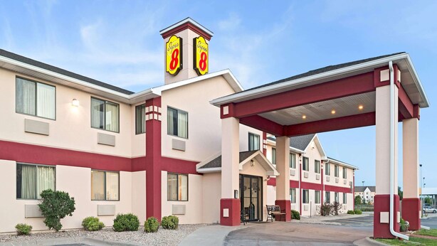 A hotel with a red and beige facade, a covered entrance, and a sign indicating it is a Super 8 hotel.